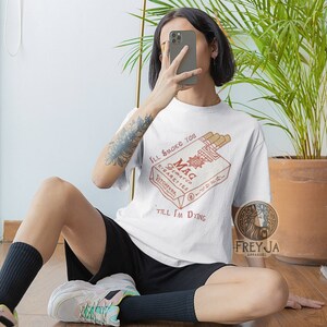 May include: White t-shirt with a graphic of a vintage cigarette pack that says "Mag Demarco Cigarettes Pitchfork" and the text "I'll smoke you 'till I'm dying".