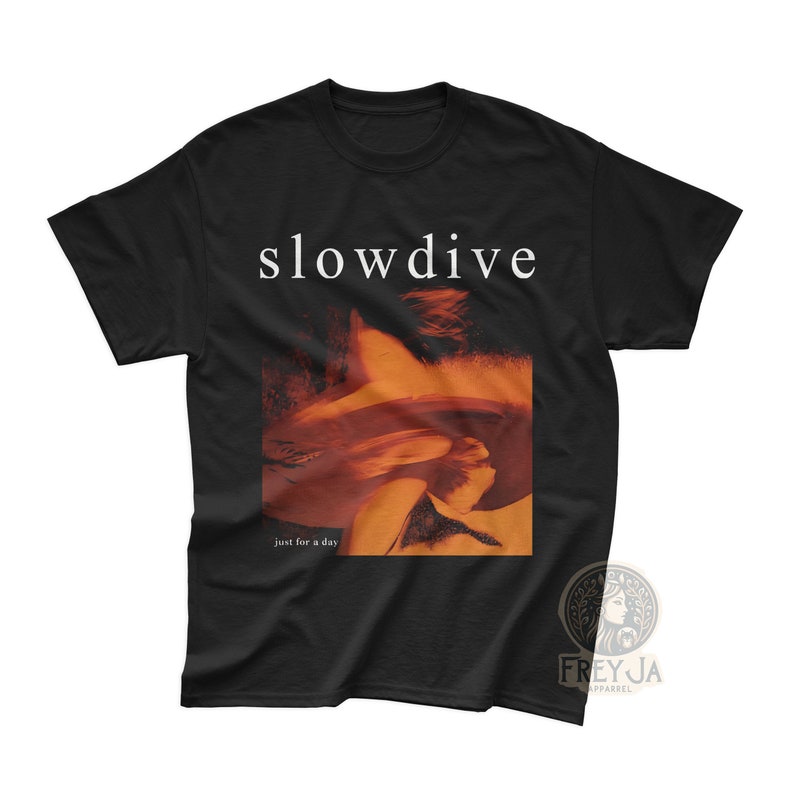 以下が含まれることがあります： 前面に白い文字で「slowdive」というバンド名がプリントされた黒いTシャツ。写真には、髪の毛で顔を隠した人が写っており、写真の真下に「just for a day」という文字が書かれている。