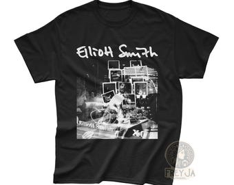 May include: Black t-shirt with a white graphic print of Elliott Smith. The graphic features a collage of photos and text.