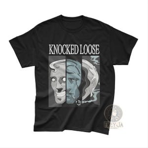 Puede incluir: Camiseta negra con el nombre de la banda "KNOCKED LOOSE" en blanco. Debajo, un gráfico de tres caras estilizadas en tonos grises y azules, con un efecto de fusión.