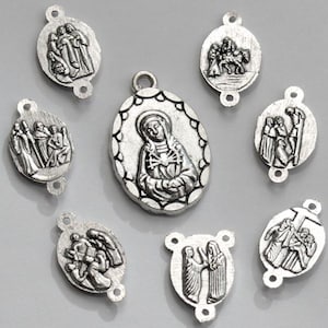 May include: A selection of silver-toned religious pendants with embossed religious scenes. The pendants are oval and rectangular, depicting religious figures and events. Each pendant has a small loop for attaching to a chain or bracelet.