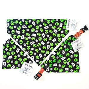 May include: A black dog collar and bandanas with a repeating pattern of green alien heads, basketballs, and the number 1. The collar is orange with a black buckle. The bandanas have white trim and tags that say "Chick Rocks".