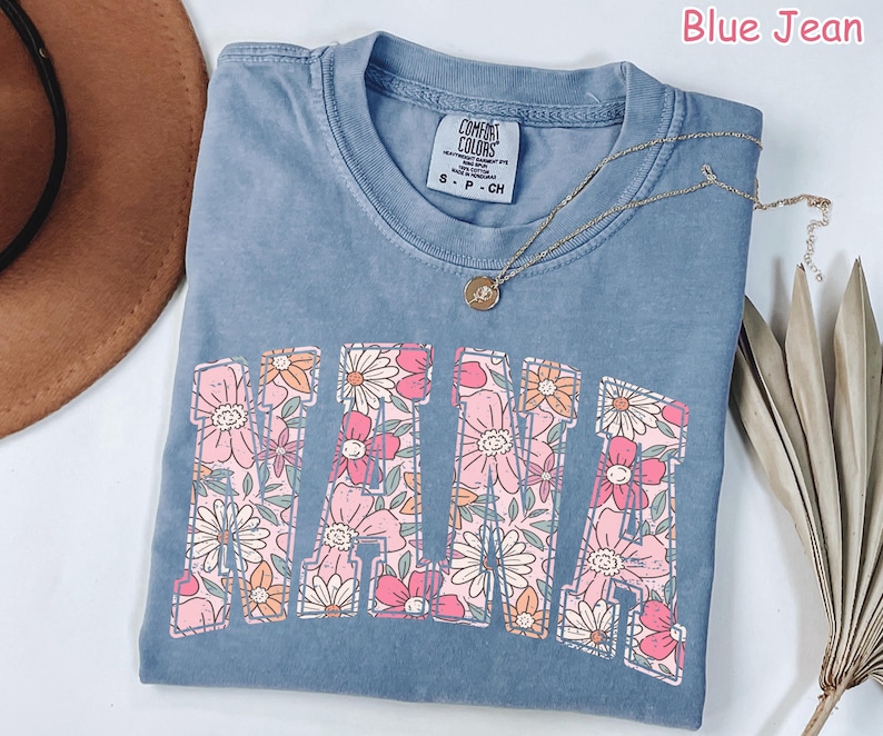 May include: A blue jean t-shirt with a floral design spelling out "MAMA". The shirt has a distressed look and is made of a soft, comfortable fabric.