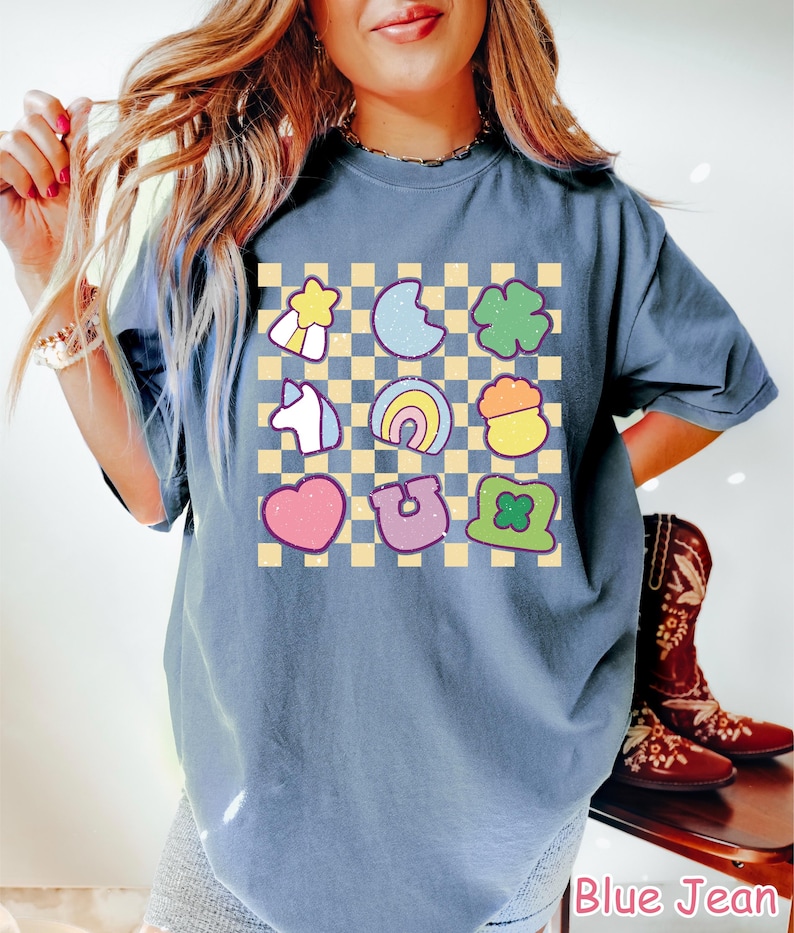 Peut inclure: Un t-shirt bleu jean &agrave; motif &agrave; carreaux avec diff&eacute;rentes images de dessins anim&eacute;s color&eacute;s, notamment un arc-en-ciel, un fer &agrave; cheval, un tr&egrave;fle &agrave; quatre feuilles, une licorne, un c&oelig;ur, une &eacute;toile, un pot d'or et un tr&egrave;fle.