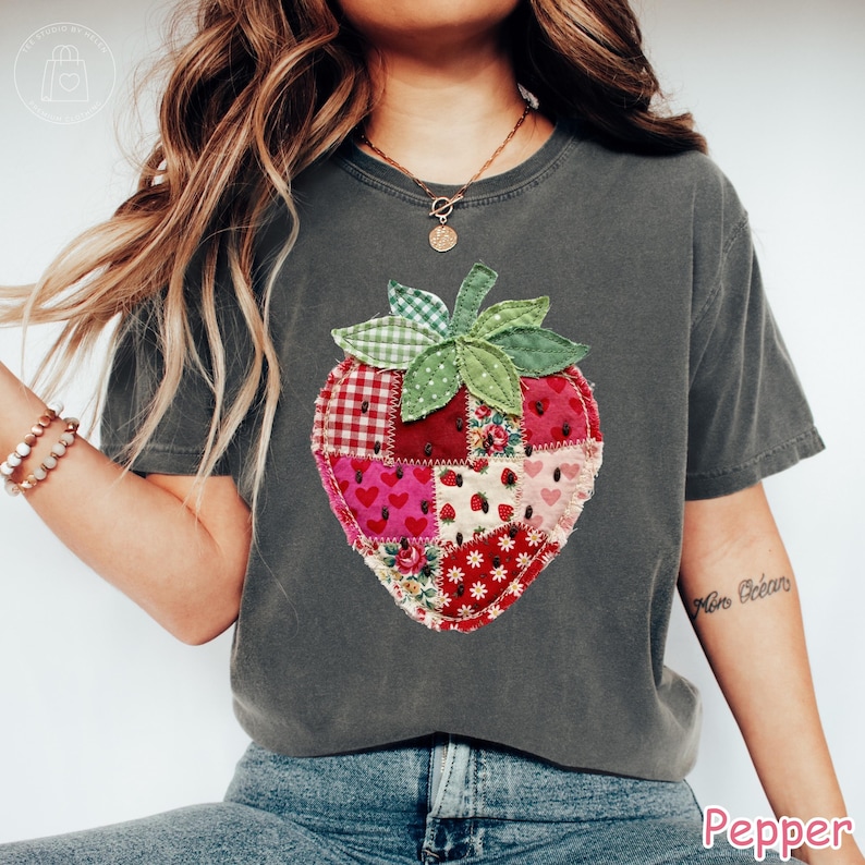 May include: Dark gray t-shirt featuring a patchwork strawberry design. The strawberry is composed of various fabric patterns, including hearts, floral prints, and gingham. The word "Pepper" is printed at the bottom right.