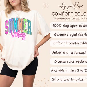 May include: Cream-colored heavyweight unisex t-shirt with the words "SUMMER Vibes" in colorful, retro-style lettering. The shirt is made of 100% ring-spun cotton and has a relaxed fit. The shirt is available in sizes S to 3XL.