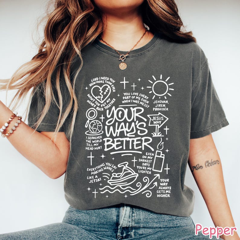 Op de afbeelding: Donkergrijs t-shirt met witte grafische tekst en illustraties. Het ontwerp bevat zinnen als "Your Way's Better", "Jesus Way" en "Even on my darkest days you're my lighter". Het t-shirt heeft een relaxte pasvorm.