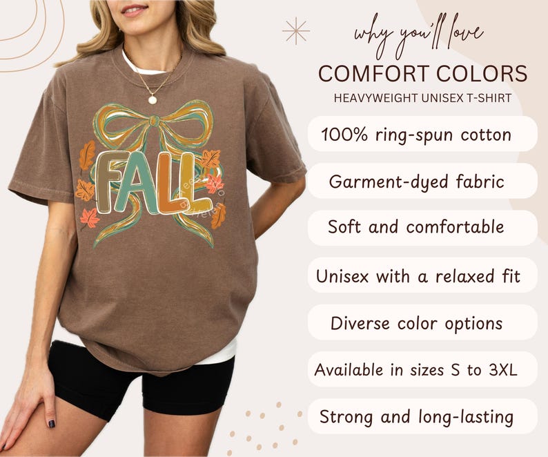 May include: Brown heavyweight unisex t-shirt with the word "FALL" in teal, orange, and brown, surrounded by a bow and autumn leaves. The shirt is made of 100% ring-spun cotton and is available in sizes S to 3XL.