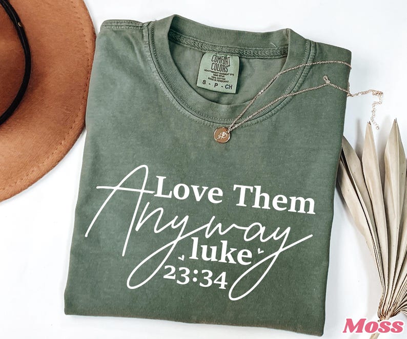 May include: Green t-shirt with white text that reads "Love Them Anyway Luke 23:34".