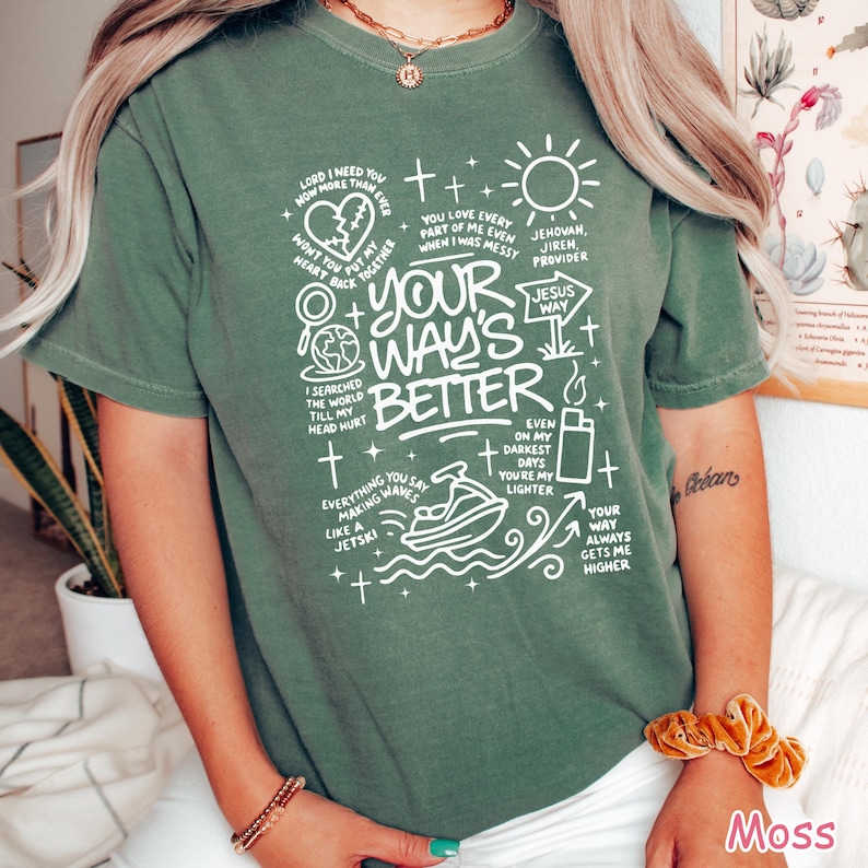 Op de afbeelding: Olijfgroen t-shirt met witte grafische tekst. De tekst bevat zinnen als "Your Way's Better" en "Jesus Way", samen met andere inspirerende berichten en illustraties. Een casual, unisex stijl.