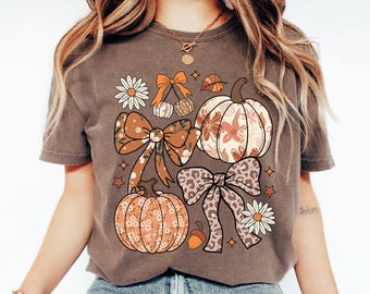 May include: Espresso-colored t-shirt featuring a fall-themed graphic. The design includes pumpkins, bows, daisies, and leaves in shades of orange, brown, and cream. The word "Espresso" is printed at the bottom right.