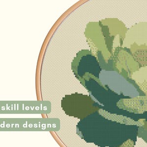 May include: Cross-stitch embroidery of a succulent plant in shades of green, blue, and beige, set within a wooden hoop. The text "All skill levels" and "Modern designs" are displayed on the left side.