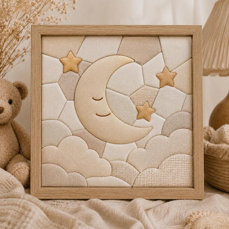 May include: A framed fabric art piece featuring a smiling crescent moon, three stars, and cloud shapes in soft beige and cream tones. The artwork is set against a geometric patchwork background and framed in light wood.
