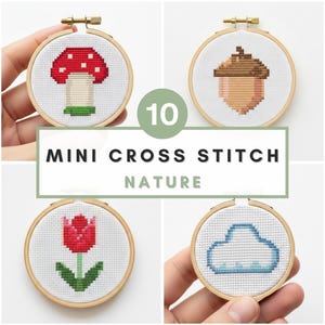 May include: A collection of ten mini cross-stitch embroidery hoops featuring nature-themed designs. The designs include a red mushroom, an acorn, a red apple, a yellow flower, a red tulip, and a blue cloud. The text "10 MINI CROSS STITCH NATURE" is displayed.