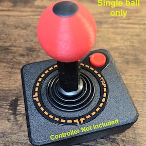 May include: A red joystick ball with a black top, attached to a black joystick base with a black and orange control panel. The control panel has the text "TOP" and "Controller Not Included".