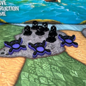 May include: A board game with black and purple game pieces. The game pieces are on a colorful game board with a water scene and the words "Creative Construction Game".