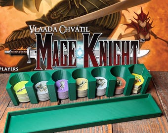 May include: Green plastic game card organizer with multiple circular compartments and a rectangular tray. The text "Vlaada Chvátil Mage Knight" is visible in the background, along with fantasy art. The organizer holds stacks of colorful game cards.