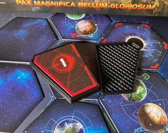 May include: A board game setup with hexagonal tiles depicting planets and space. A red and black card with the number 1 is visible, along with a black, textured game piece. The game's title, "PAX MAGNIFICA BELLUM GLORIOSUM", is at the top.