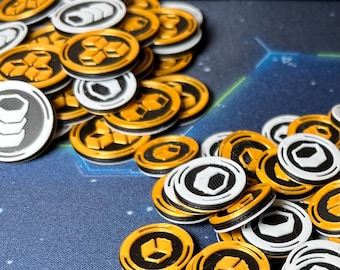 May include: A collection of game tokens in various designs. The tokens are primarily white, black, and gold. Some tokens feature geometric shapes, while others have a stack of coins design. The tokens are scattered on a blue surface.