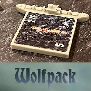 Könnte beinhalten: Ein hellgraues Miniatur-Kriegsschiffmodell mit einer rechteckigen Karte mit einer Schiffsillustration auf dunklem Meer. Die Karte trägt die Texte "2VP", "3.000T" und den Buchstaben "S". Das Wort "Wolfpack" steht unten.