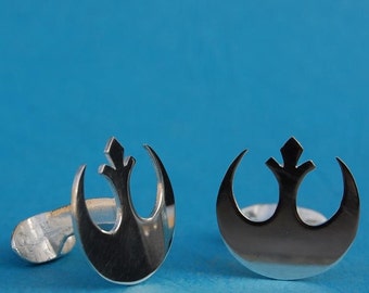 May include: A pair of silver cufflinks featuring the Rebel Alliance symbol from Star Wars. The symbol is a stylised crescent moon with a small triangle in the centre.