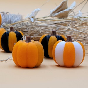 Puede incluir: Una colección de pequeñas calabazas pintadas a mano en naranja, negro y blanco. Algunas calabazas tienen rayas negras, mientras que otras tienen rayas blancas.