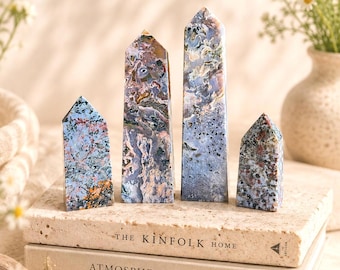 May include: Four polished stone towers with pointed tops, featuring a complex pattern of blue, grey, brown, and black inclusions. The stones are arranged in a row, displaying varied heights and widths with a smooth, reflective surface texture.
