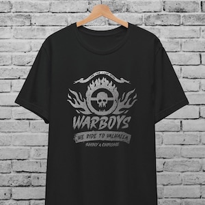 Puede incluir: Camiseta negra con un gráfico plateado de una calavera y llamas. El gráfico dice "I Live I Die I Live Again" y "Warboys We Ride To Valhalla Shiny & Chrome".
