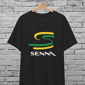 Może przedstawiać: Czarny T-shirt z zielono-żółtym logo "S" i napisem "SENNA" w białym kolorze.