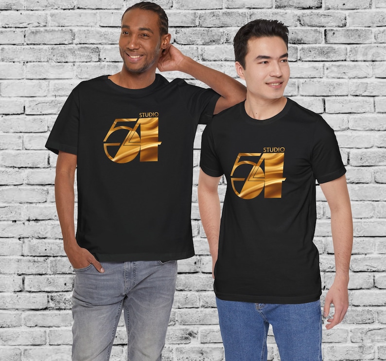 May include: Two people wearing black t-shirts with a gold graphic of the number 54 and the word "Studio" above it. The graphic has a metallic sheen.