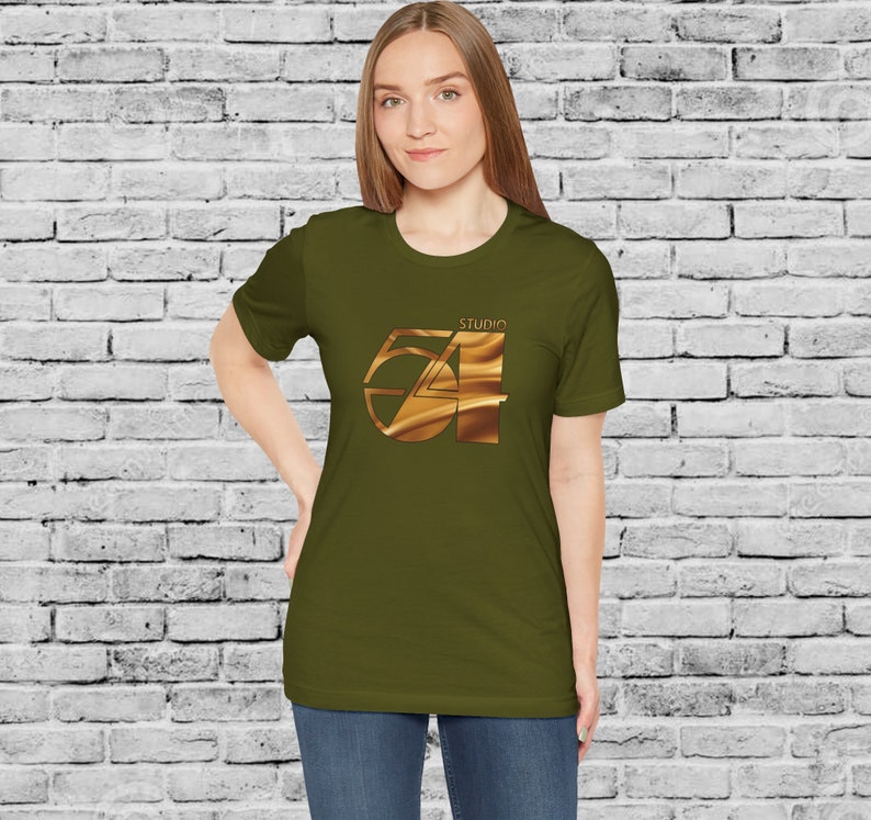 May include: A woman wearing a green t-shirt with a gold graphic of the number 54 with the word "Studio" above it.