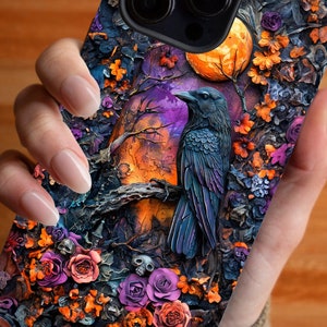 May include: A black phone case with a detailed design of a raven perched on a branch with a full moon in the background. The design features a variety of flowers in shades of purple, orange, and pink.