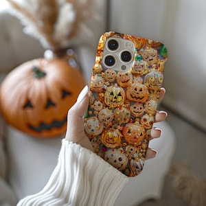May include: A phone case with a colorful pattern of jack-o'-lanterns. The case is designed for an iPhone with a camera lens cutout.