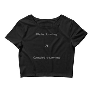 May include: Black crop top with the text "Attached to nothing" above a white Om symbol and the text "Connected to everything" below. The shirt has short sleeves and a rounded neckline. The text and symbol are centered.