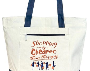 May include: Cream-colored tote bag with navy blue accents. The bag features a zippered pocket and navy blue handles. The phrase "Shopping is Cheaper than Therapy" is printed in glittery orange, with silhouettes of shoppers below.