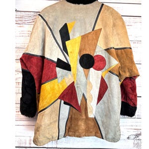 May include: A vintage suede jacket with an abstract geometric design in shades of tan, brown, red, yellow, and black. The jacket features a black fur collar and cuffs, and a patchwork design on the back.