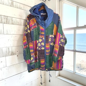 May include: A long-sleeve hooded jacket featuring a vibrant patchwork design with various geometric and floral patterns in shades of blue, green, purple, yellow, and pink. The jacket includes a full-length front zipper, a drawstring hood, and a drawstring hem.