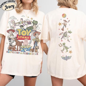 Op de afbeelding: Een ivoorkleurig t-shirt met Toy Story-personages op de voor- en achterkant. De voorkant toont een grote groep personages met het Toy Story-logo en de tekst You've Got A Friend In Me. De achterkant toont een verticale opstelling van figuren.