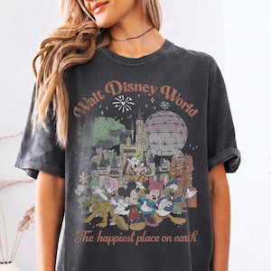 May include: Dark gray t-shirt featuring a colorful graphic of Disney characters and landmarks, including Mickey Mouse, Minnie Mouse, and Cinderella's castle. The text "Walt Disney World" and "The happiest place on earth" are printed on the shirt.