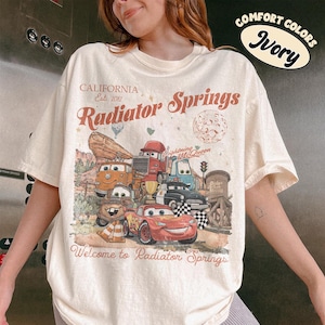 以下が含まれることがあります： 「Cars」のキャラクターのグラフィックがプリントされたアイボリー色のTシャツ。「California Est. 2012 Radiator Springs」と「Welcome to Radiator Springs」の文字入り。「Comfort Colors」のラベル付き。