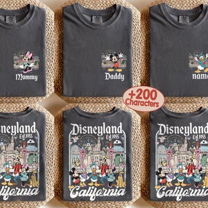 May include: Six dark gray t-shirts. Three shirts have Disney character designs with the words "Mommy", "Daddy", and "name". The other three shirts have a Disneyland graphic with the words "Disneyland Est. 1955 California".