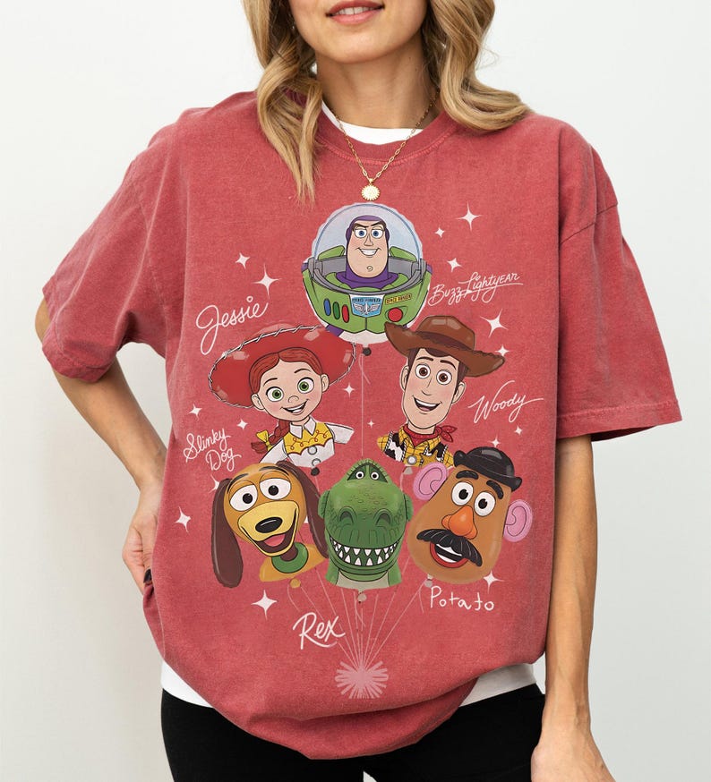 Puede incluir: Camiseta rojo-naranja con personajes de dibujos animados de la pel&iacute;cula Toy Story. El dise&ntilde;o incluye a Jessie, Buzz Lightyear, Woody, Slinky Dog, Rex y Mr. Potato. Los nombres de los personajes est&aacute;n escritos en una fuente l&uacute;dica.