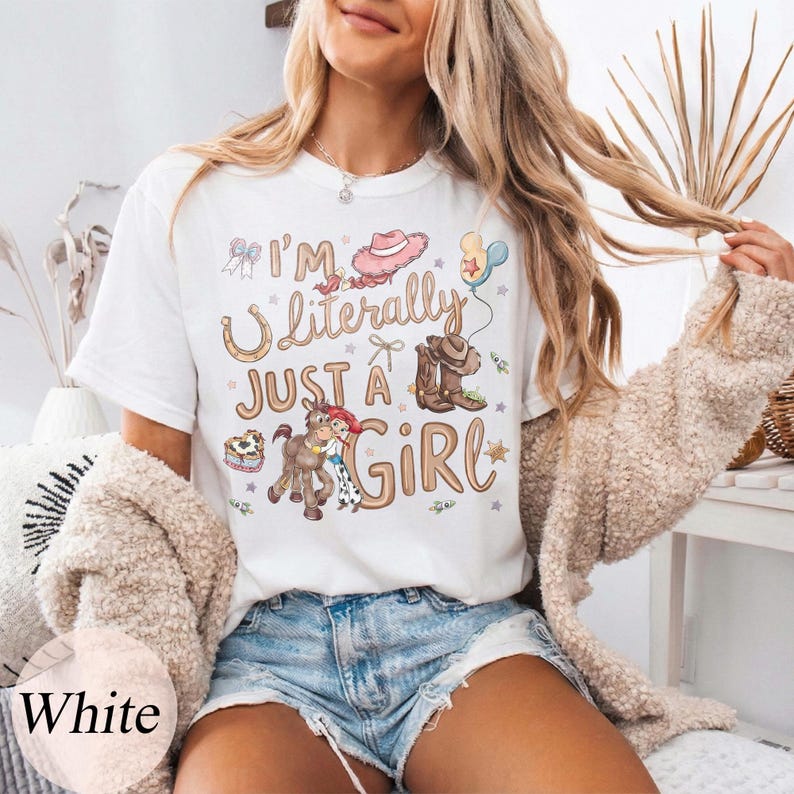 K&ouml;nnte beinhalten: Wei&szlig;es T-Shirt mit dem Text "I'm Literally Just a Girl" und einer Grafik mit Cowboyhut, Stiefeln und einem Pferd. Das Design enth&auml;lt Pastellfarben und Sterne. Das T-Shirt hat einen Rundhalsausschnitt und kurze &Auml;rmel.