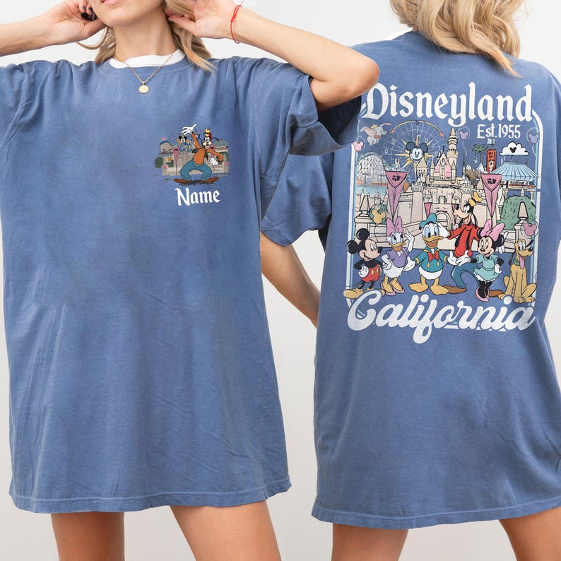 May include: Blue t-shirt with a white collar featuring a Disneyland graphic. The front has a cartoon image and the word "Name". The back displays a Disneyland scene with characters and the text "Disneyland Est. 1955 California".