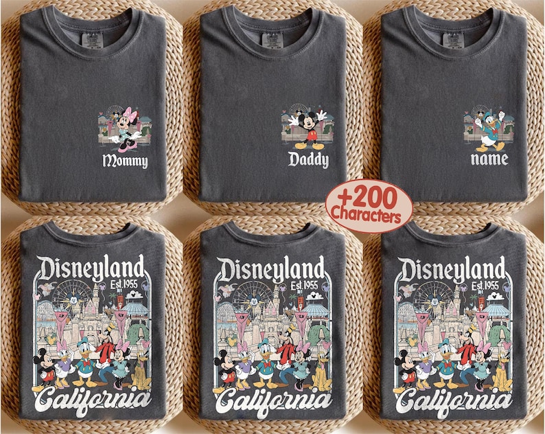 May include: Six dark gray t-shirts. Three shirts have Disney character designs with the words "Mommy", "Daddy", and "name". The other three shirts have a Disneyland graphic with the words "Disneyland Est. 1955 California".