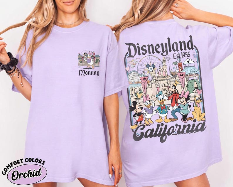 May include: A light purple t-shirt with a Disneyland graphic on the back and a small graphic with the word "Mommy" on the front. The Disneyland graphic features Mickey Mouse and friends in front of a castle.