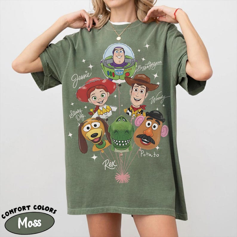 Puede incluir: Camiseta Comfort Colors verde musgo con un gr&aacute;fico de los personajes de Toy Story: Buzz Lightyear, Woody, Jessie, Slinky Dog, Rex y Mr. Potato Head. La camiseta tiene el texto "Jessie", "Woody" y "Potato".