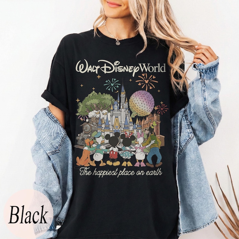 Puede incluir: Camiseta negra con un gr&aacute;fico colorido de Walt Disney World, que incluye monumentos emblem&aacute;ticos, fuegos artificiales y personajes de Disney. El texto "Walt Disney World" y "The happiest place on earth" est&aacute;n impresos.