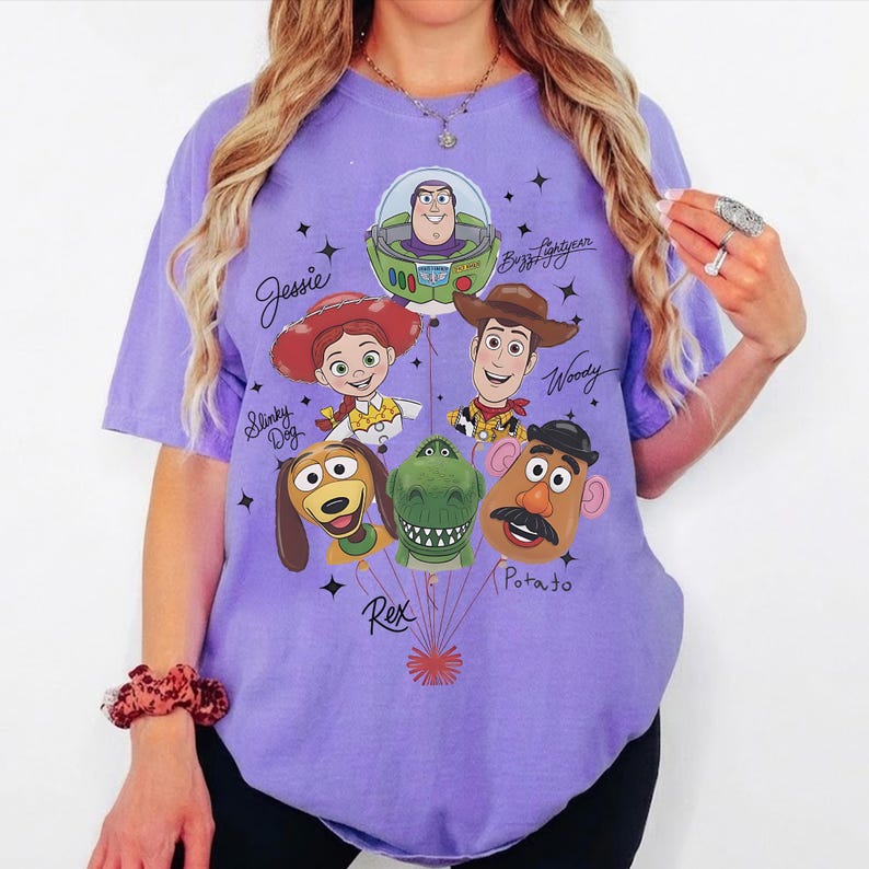 Puede incluir: Una camiseta de color lila con un dise&ntilde;o de personajes de Toy Story. El dise&ntilde;o incluye a Buzz Lightyear, Woody, Jessie, Slinky Dog, Rex y Mr. Potato. Los nombres de los personajes est&aacute;n escritos en una fuente caprichosa, con estrellas.