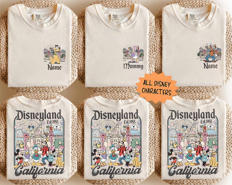 May include: Cream-colored t-shirts with Disney character graphics. Some shirts have "Name" or "Mommy" text. The bottom shirts feature a Disneyland graphic with "California" text and "Est. 1955". The shirts are displayed on woven mats.
